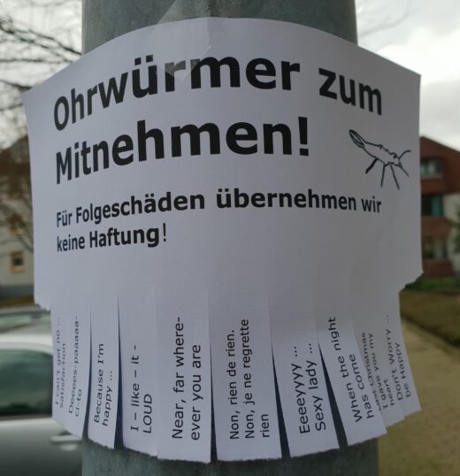 Zettel an einem Laternenpfahl "Ohrwürmer zum Mitnehmen"